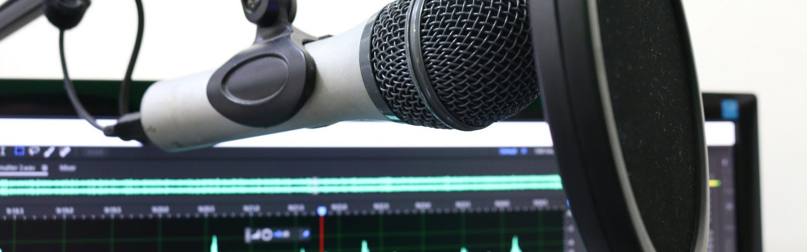 Image of a Microphone in front of a computer with an audio file open.