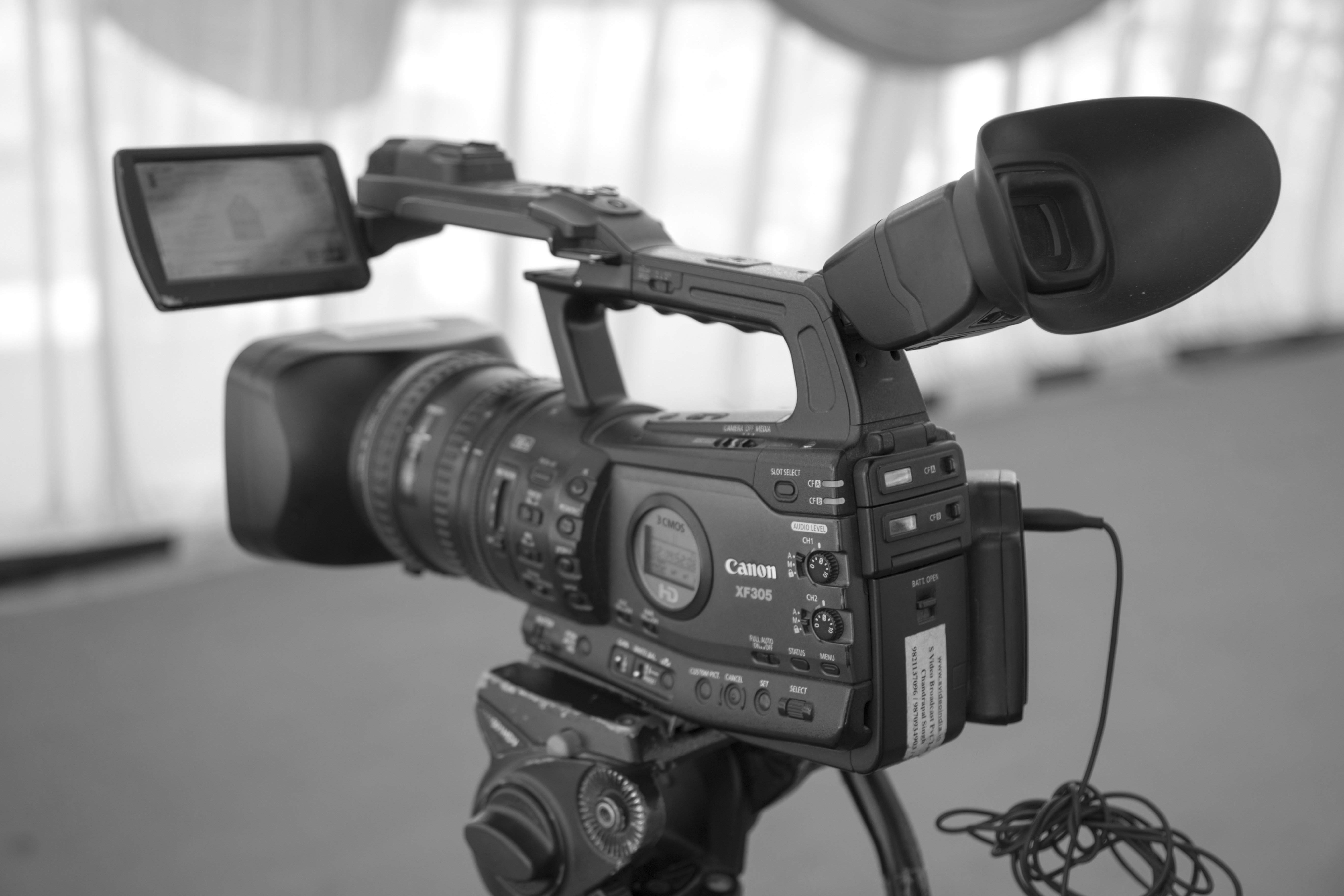 Black and white image of a professional video camera on a tripod