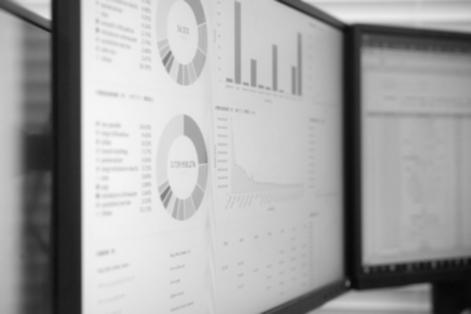 Black and white photo of 2 computer monitors displaying charts and graphs