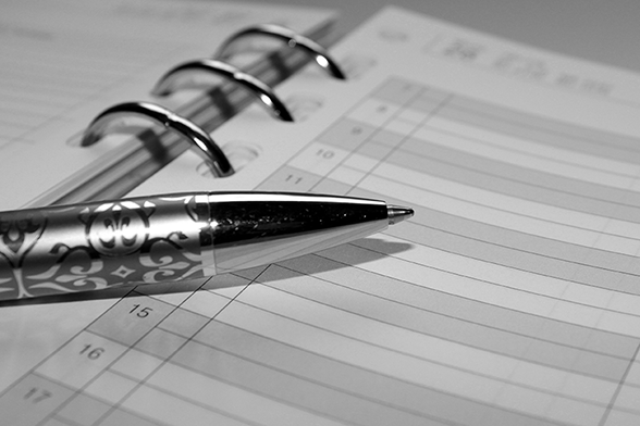 Black and white image of a planner book with a ballpoint pen on it