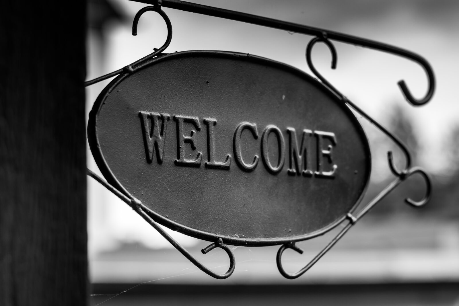 Black and white photo of a metal welcome sign